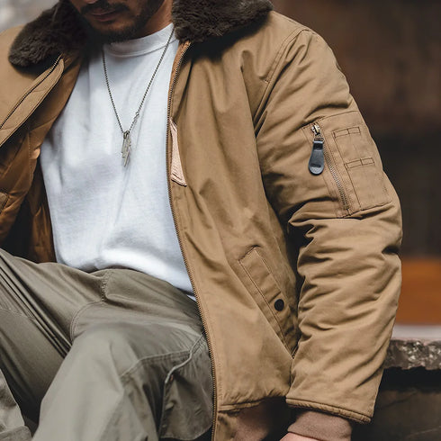 Person wearing a brown jacket with fur lining, white shirt, and green pants.